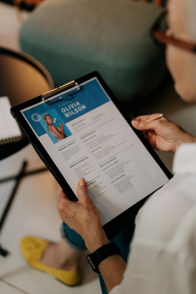 pexels-photo-5989925-5989925 An HR professional reviews a resume on a clipboard during an office meeting.